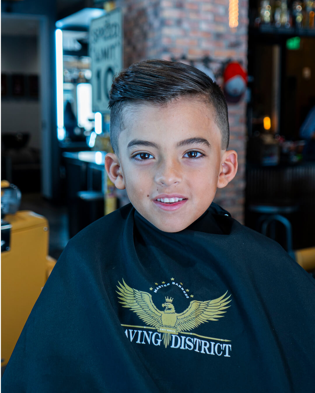 Young client smiling in a Shaving District cape